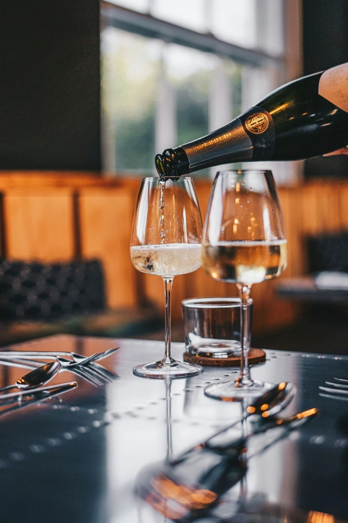 a person pouring a glass of white wine